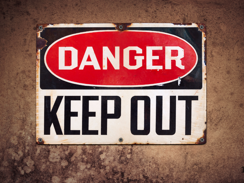 Warning sign with the words "DANGER KEEP OUT" on a weathered metal plate.